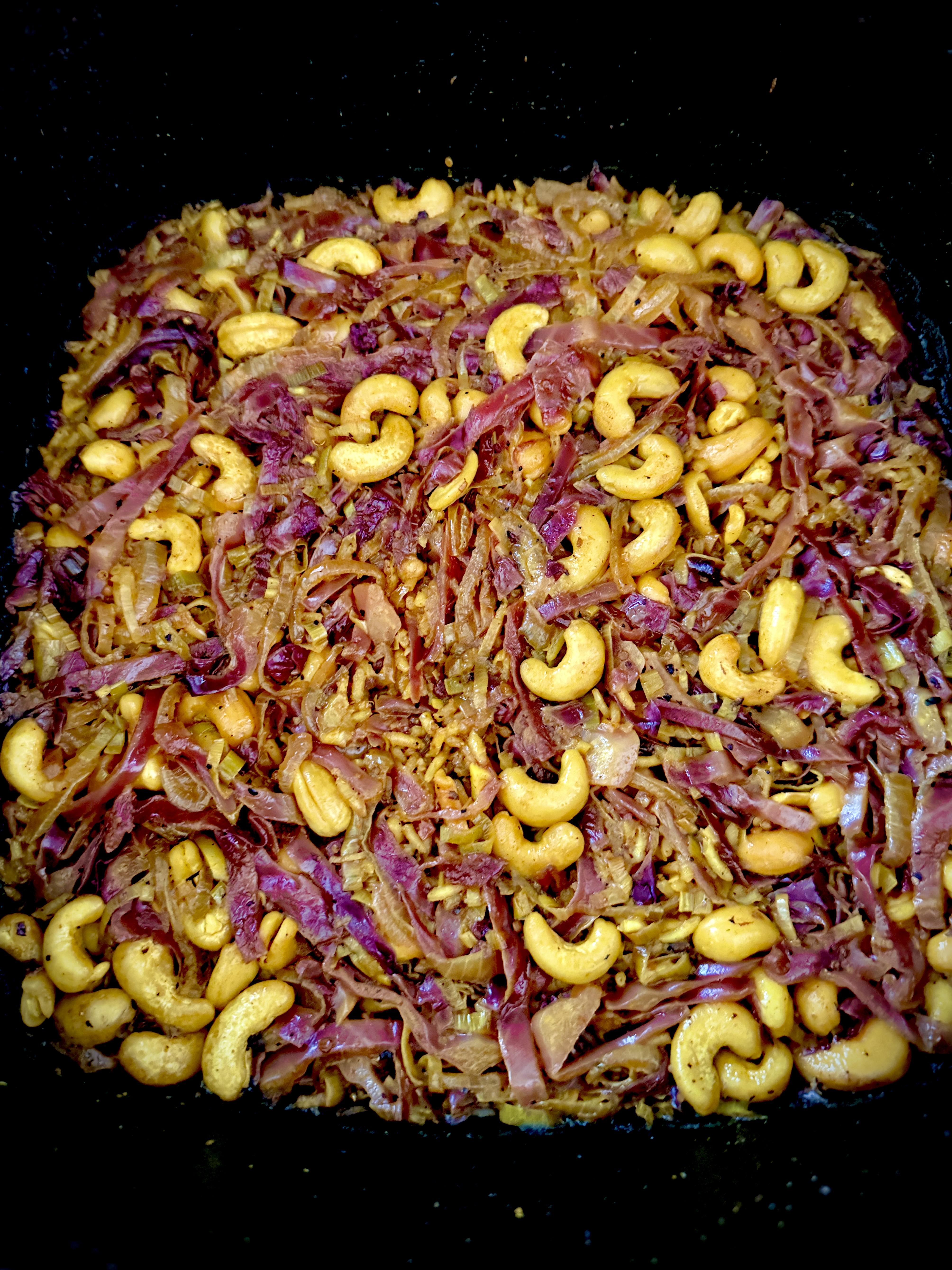 Red cabbage biryani in the pan, showing the braised purple cabbage ribbons and turmeric-stained cashews