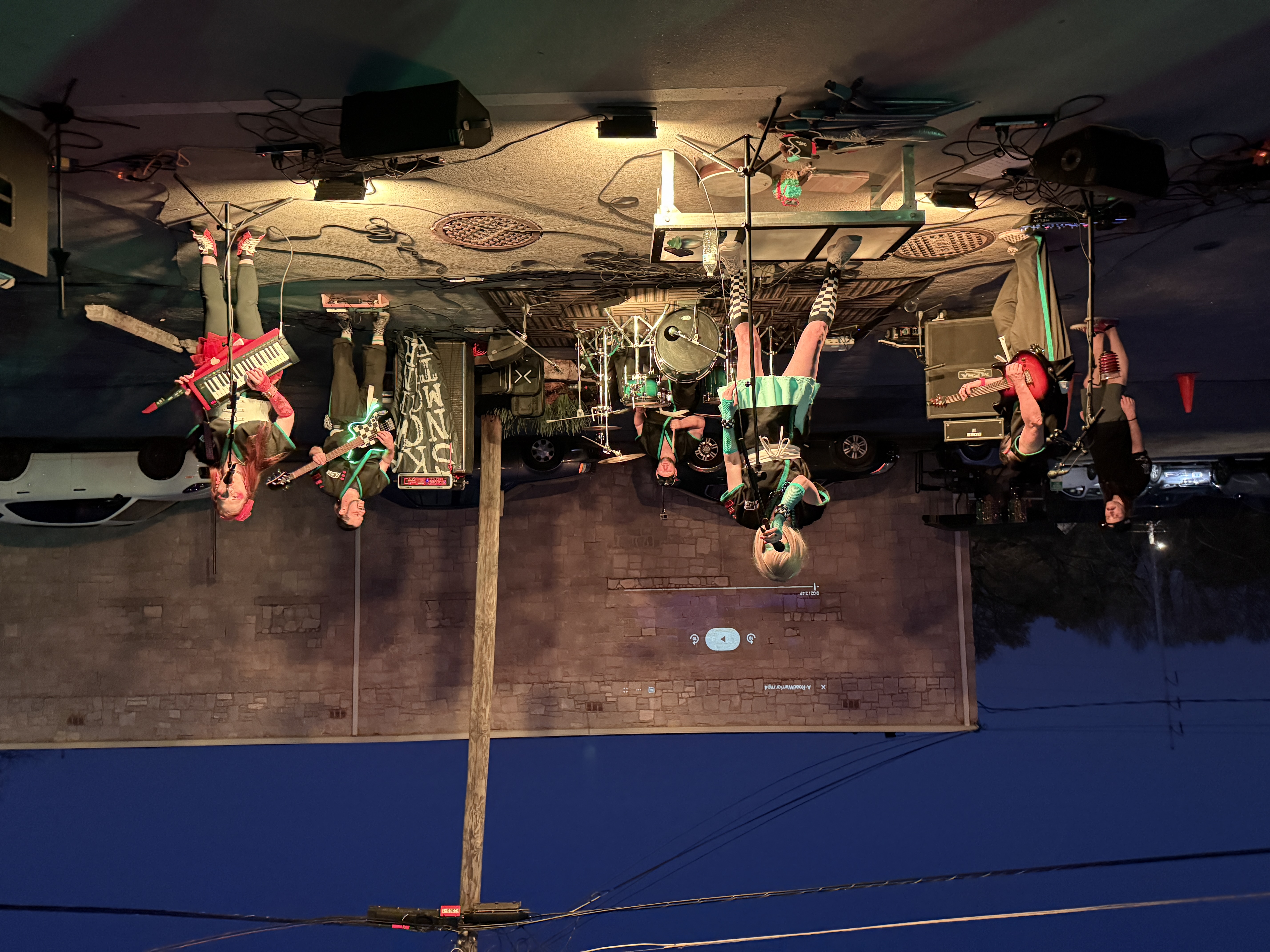 Space Mutiny performing in the Outrun Brewing Company parking lot, with a movie projected on the building wall behind them