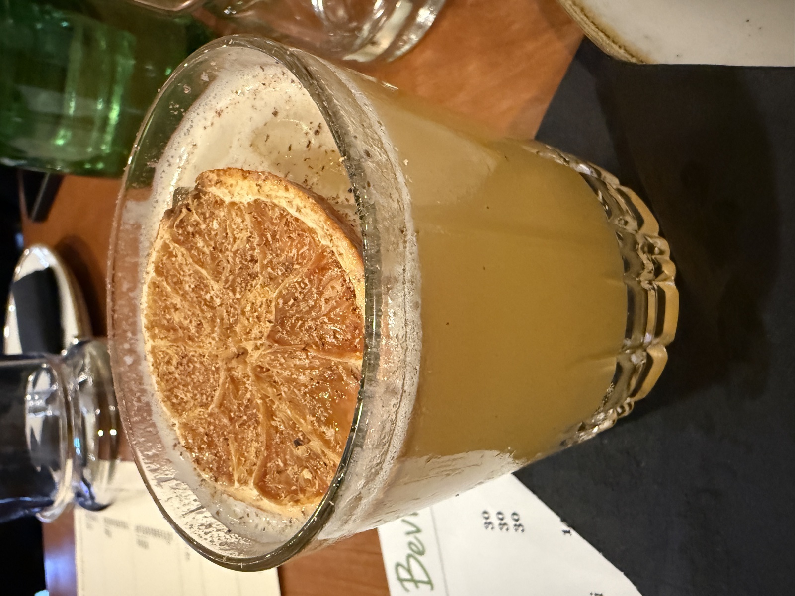 A citrus cocktail with a dehydrated lemon wheel garnish, served in a rocks glass at a bar in the San Carlos area
