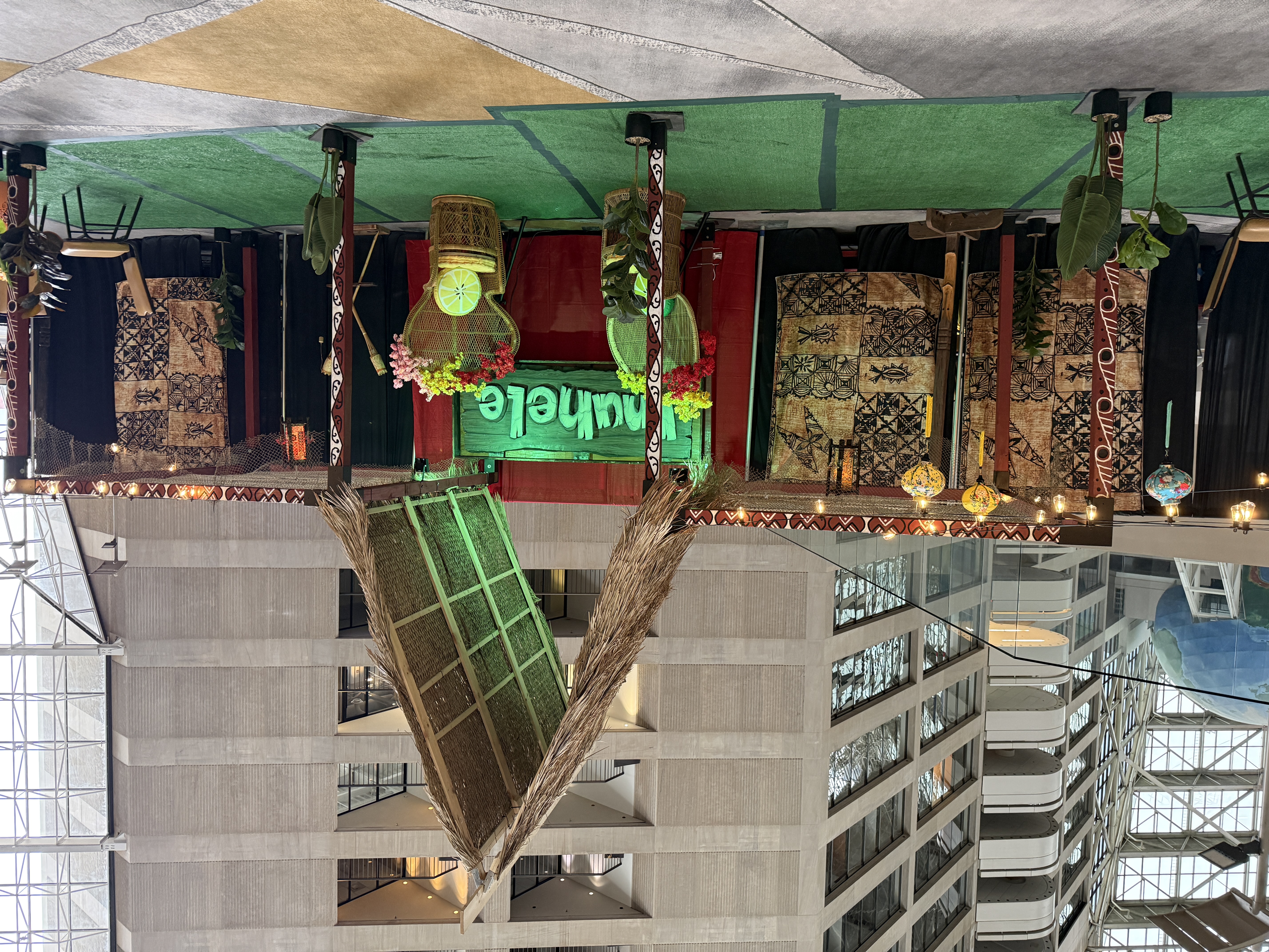 Main Inuhele stage with thatched roof, tapa cloth backdrop, and peacock chairs under string lights