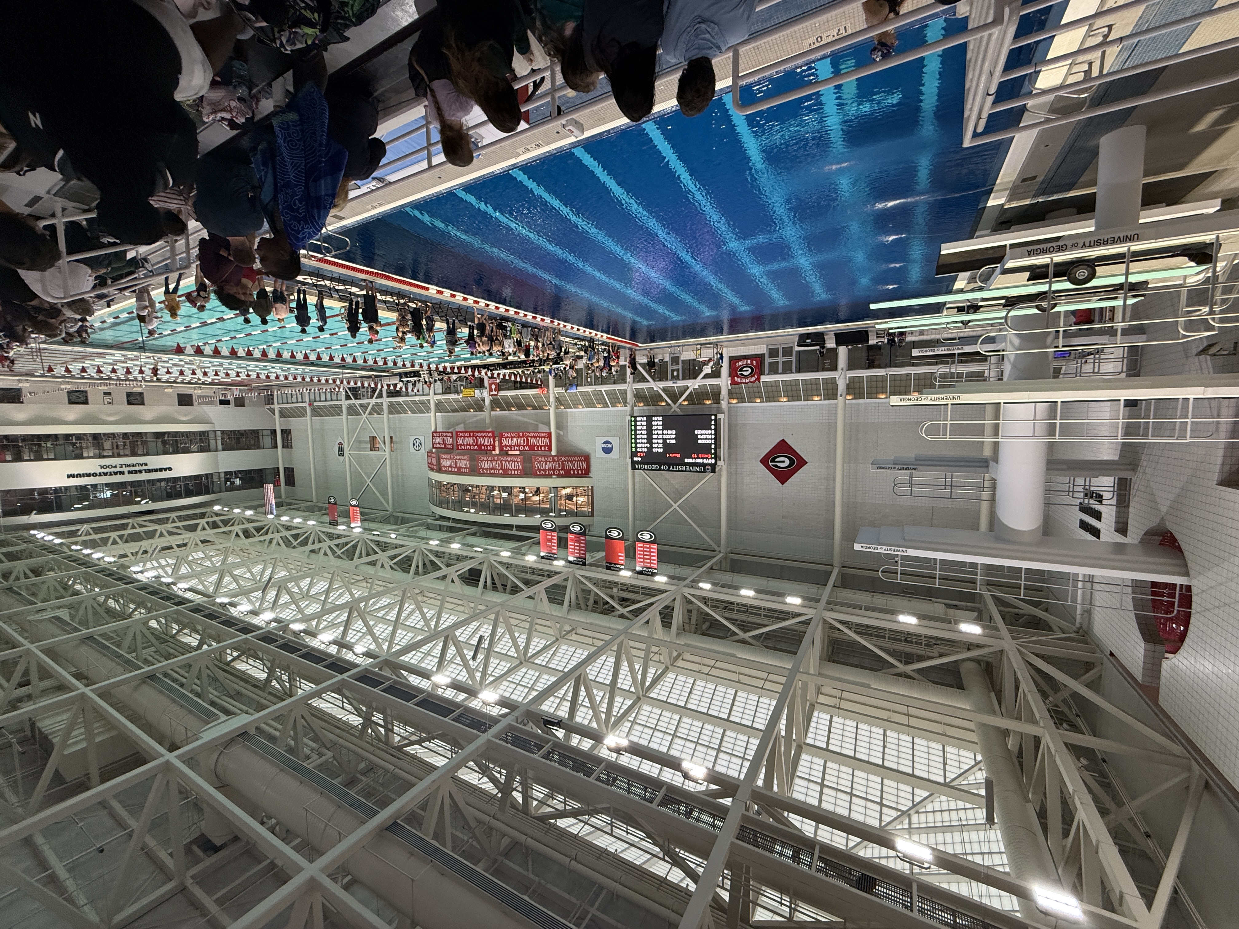 The UGA Gabrielsen Natatorium, showing the diving well, competition pool, and championship banners under the massive steel truss ceiling