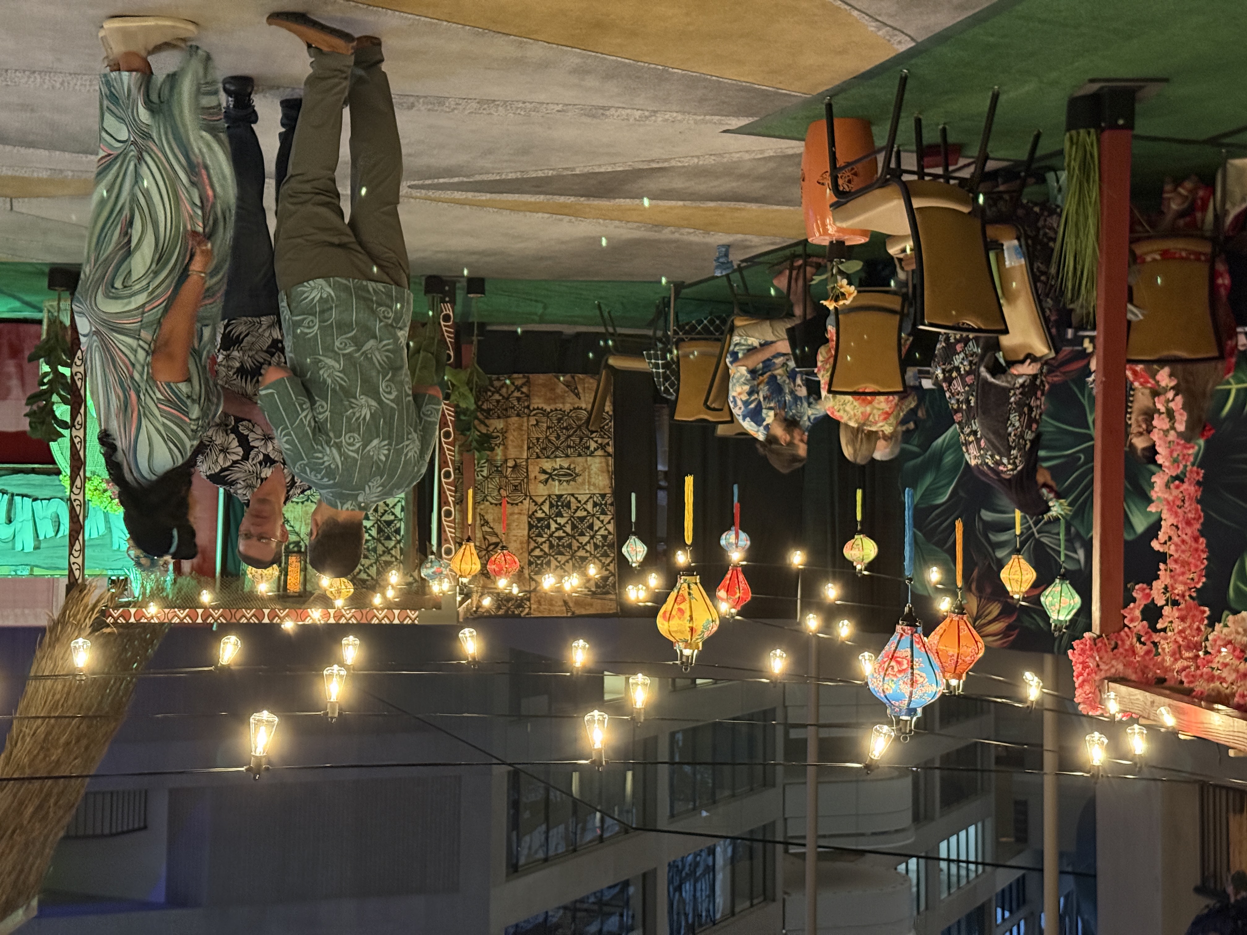 Evening scene at Inuhele with string lights, colorful lanterns, and attendees in Hawaiian shirts mingling