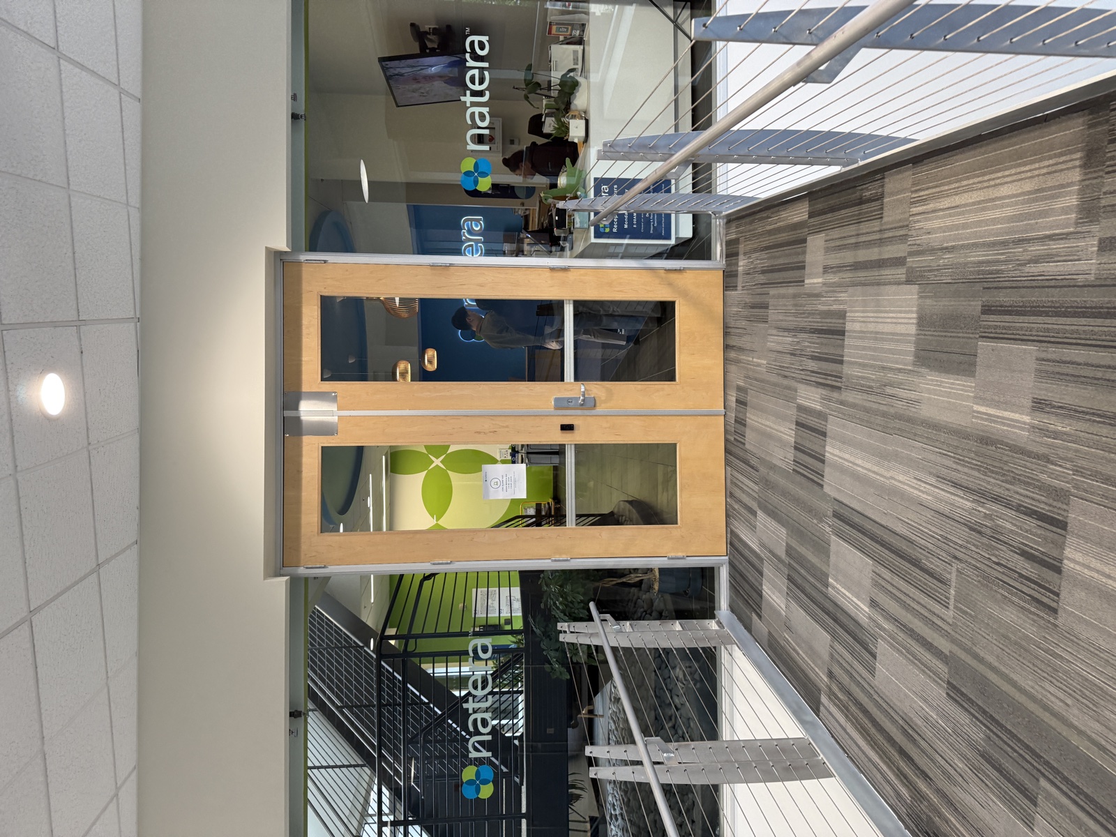 The entrance to the Natera office in San Carlos, California, with the company logo on the glass walls flanking a set of wooden doors